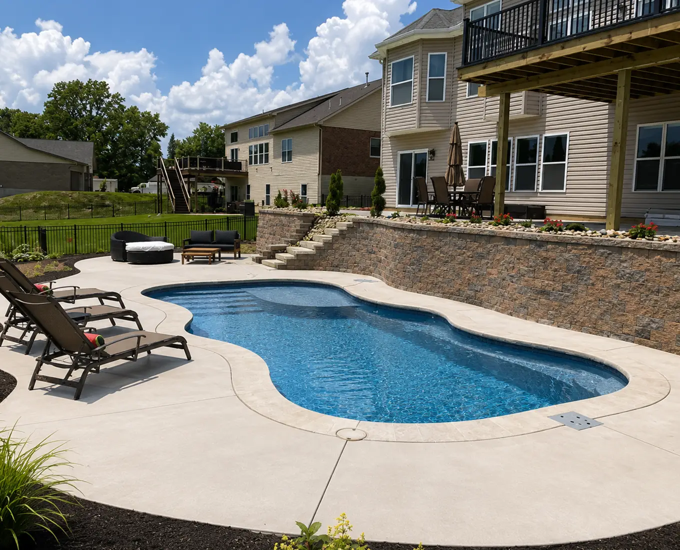 Backyard fiberglass pool with lounge chairs and elevated patio at a home in Columbia, Illinois.