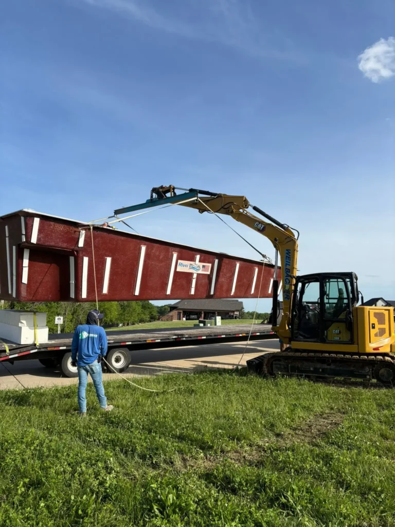 River Pools fiberglass pool shell being lifted by excavator during residential pool installation in Columbia, IL.