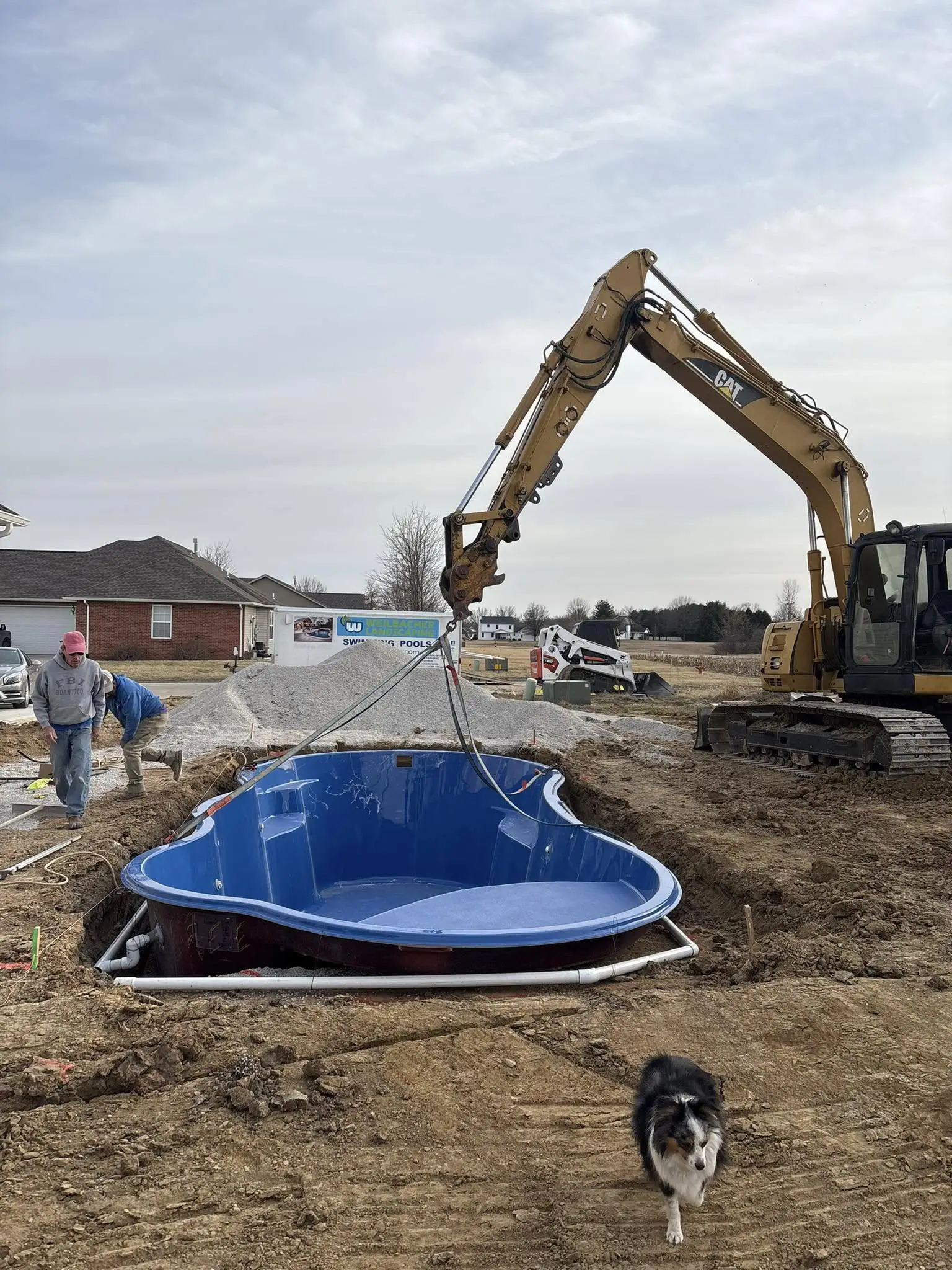 Fiberglass pool installation in progress with excavator placing pool shell into prepared excavation site in Columbia, Illinois.