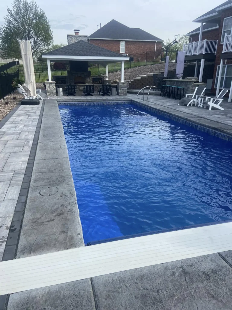 Custom fiberglass swimming pool with outdoor kitchen, covered pavilion, and spacious entertainment area in Columbia, Illinois.